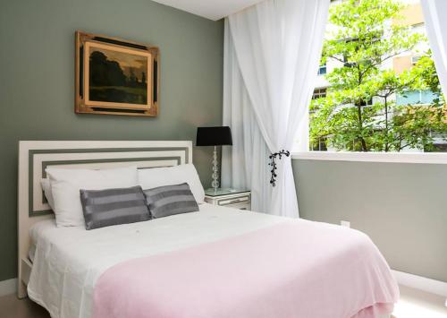 リオデジャネイロにあるLeblon Dream Apartmentのベッドルーム(白いベッド1台、窓付)