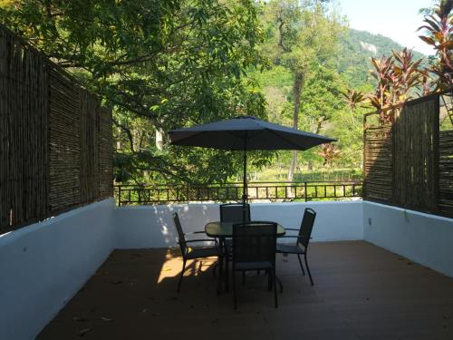 a patio with a table and chairs and an umbrella at Hotel Azul Esmeralda in Teapa