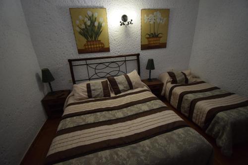 a bedroom with two beds and two pictures on the wall at Apartamentos Horno y Casa De Dulce in Purullena