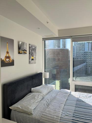 a bedroom with a bed and a large window at Beautiful one bedroom downtown Condo with pool and free parking in Montreal