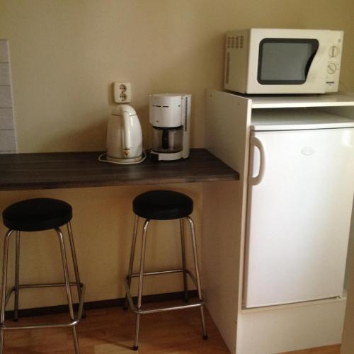 a kitchen with two bar stools and a microwave at Hotel Lamminpää in Tampere