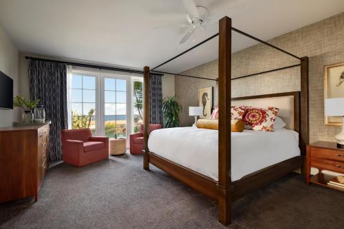 Terranea Resort في رانتشو بالوس فيرديس: غرفة نوم بسرير مظلة وكرسي