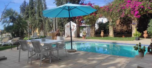 una mesa con sombrilla junto a la piscina en Lovely Guesthouse in Benajarafe en Benajarafe