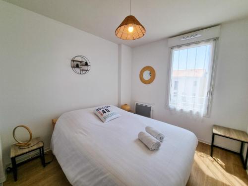 une chambre avec un lit blanc avec deux serviettes dessus dans l'établissement La cabane de Mimimael Duplex 4 pers proche océan, à Mimizan