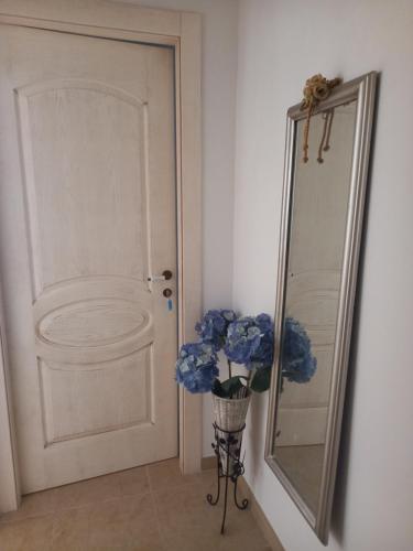 a vase of blue flowers in front of a mirror at Casa venere in Pachino