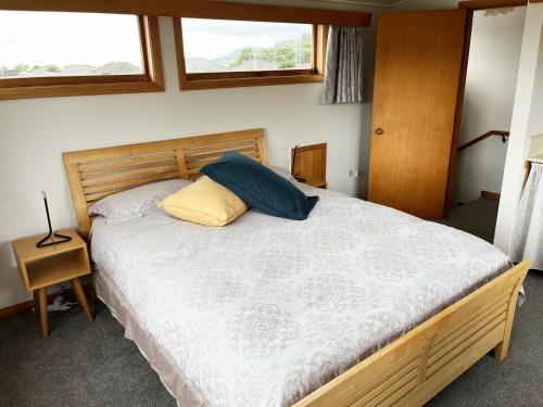 a bedroom with a bed with a wooden headboard and two pillows at Maitai River Romance - in Town in Nelson