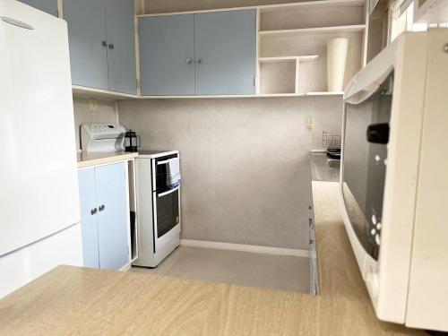 a small kitchen with white cabinets and a refrigerator at Maitai River Romance - in Town in Nelson