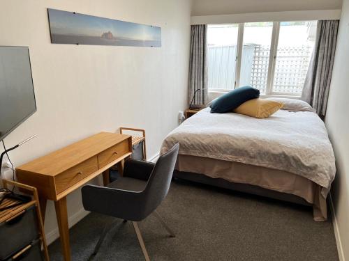 a bedroom with a bed and a desk and a television at Maitai River Romance - in Town in Nelson