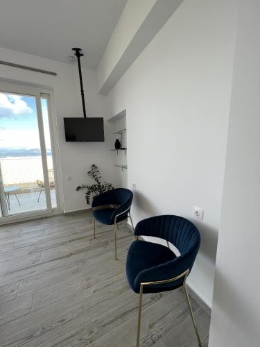 two blue chairs in a room with a view of the ocean at Greco Mare in Kavos