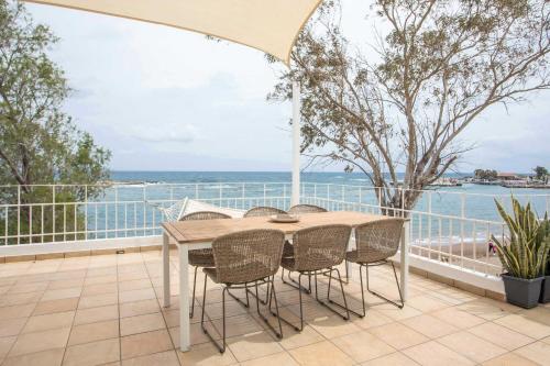 a table and chairs on a balcony with a view of the ocean at Salty Beach Front House Faliraki in Faliraki