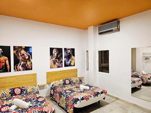 a room with two beds and posters on the wall at Arc House Plaza in Seville