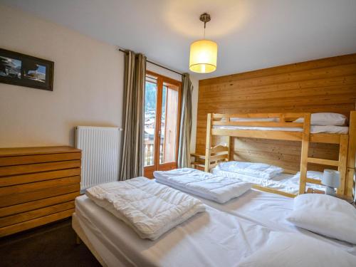 une chambre avec deux lits superposés avec des draps blancs dans l'établissement Appartement Morzine 64m² - Proche remontées mécaniques, WiFi, Sauna, Parking, 6 Pers. - FR-1-684-61, à Morzine