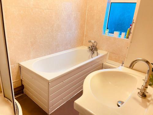 a bathroom with a white tub and a sink at Inviting 3 -Bed House in Birmingham in Birmingham