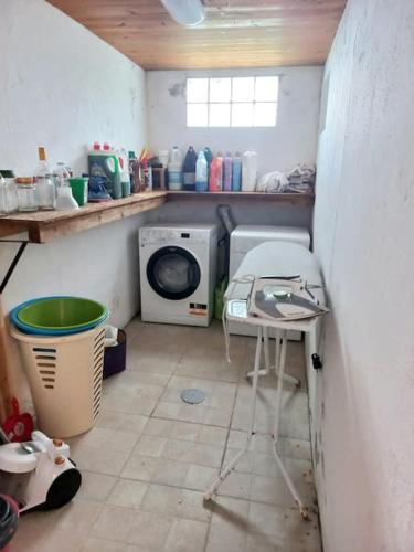 a laundry room with a washing machine and a table at Um quarto da Casa Do Monte in Água de Alto