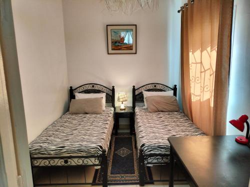 2 Einzelbetten in einem Zimmer mit einem Tisch in der Unterkunft Appartement calme et confortable in Al Ghar