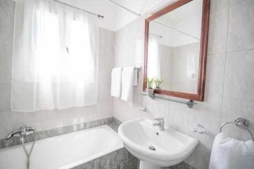 a white bathroom with a sink and a mirror at Christoforos Apartments in Lourdata