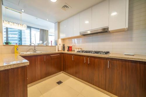 FIRST CLASS 3BR with full BURJ KHALIFA and FOUNTAIN VIEW في دبي: مطبخ كبير مع خزائن خشبية ومغسلة