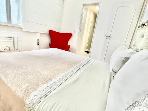 1 dormitorio con 1 cama blanca y 1 silla roja en Ipanema Beach lovely apartment, en Río de Janeiro