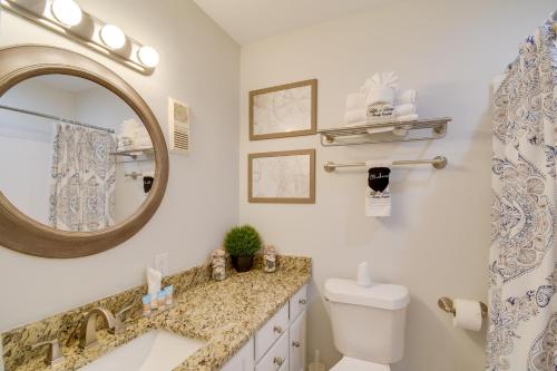 ein Badezimmer mit einem Waschbecken, einem WC und einem Spiegel in der Unterkunft Vibrant Gulf Shores Getaway with Pool and Beach Access in Gulf Shores