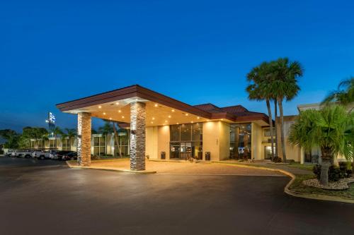 a hotel with a parking lot and palm trees at Best Western International Speedway Hotel in Daytona Beach