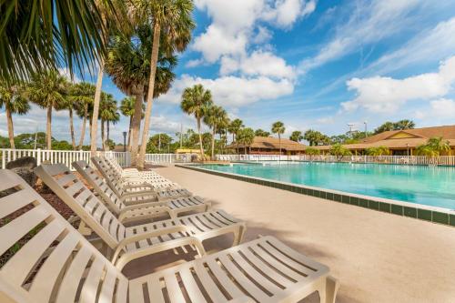 a row of white lounge chairs next to a swimming pool at Best Western International Speedway Hotel in Daytona Beach