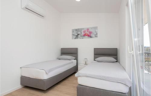 2 łóżka w pokoju z białymi ścianami i oknem w obiekcie Lovely Home In Donji Prolozac With Wifi w mieście Donji Proložac
