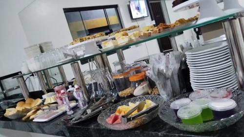 ein Buffet mit Tellern und Schalen von Speisen auf der Theke in der Unterkunft Hotel Enlace in Ji-Paraná