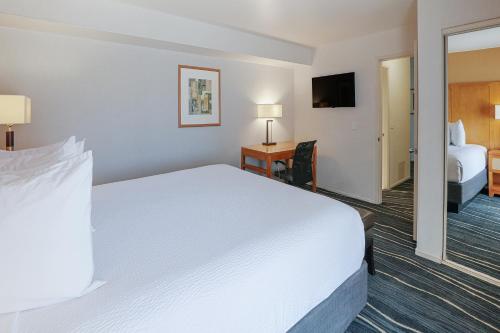 a hotel room with a large white bed and a bedroom at Ramada by Wyndham Costa Mesa/Newport Beach in Costa Mesa
