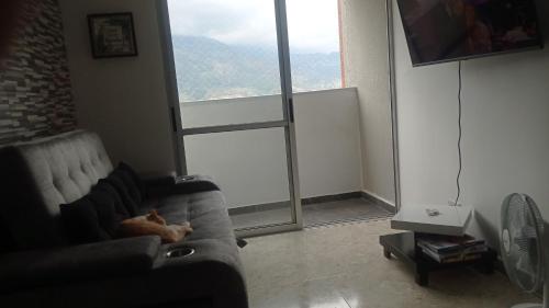 eine Katze, die auf einer Couch im Wohnzimmer mit Fenster liegt in der Unterkunft Travelers home in Bello