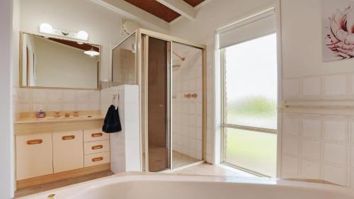 a white bathroom with a tub and a shower at 41 Collins Street Merimbula in Merimbula