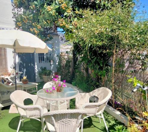 een patio met een tafel en stoelen en een parasol bij Casa Mila in Fuengirola