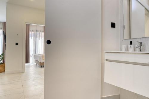 a white bathroom with a sink and a mirror at Beco Santa Emilia 3M, a Home in Madeira in Funchal