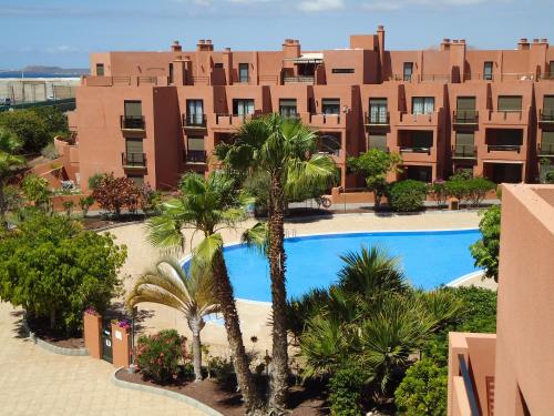 um complexo de apartamentos com piscina e palmeiras em Atico La Tejita relax em Granadilla de Abona