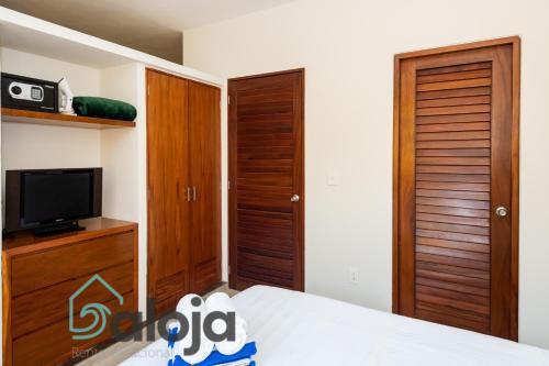a bedroom with a bed and a tv and wooden doors at Ideal estudios cálidos y acogedores in Cancún