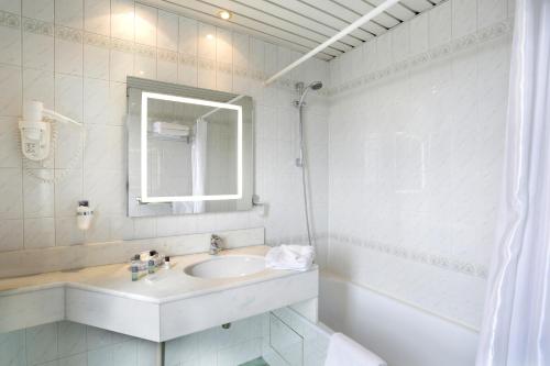 a white bathroom with a sink and a mirror at Hotel Paix Republique in Paris