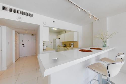 a white kitchen with a counter and two chairs at Decoplage Paradise - Unit B in Miami Beach