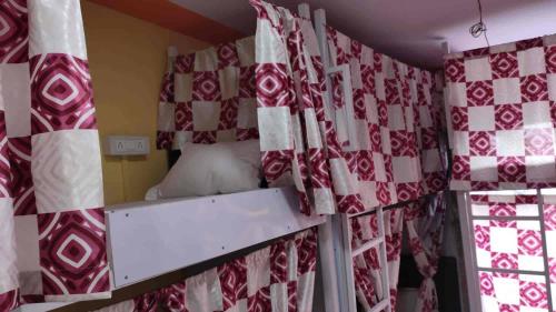 a room with a bed with red and white curtains at Indian Drom Hostel-PG in Mumbai
