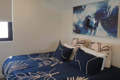 - une chambre dotée d'un lit bleu avec des oreillers et un tableau dans l'établissement 1011 Arena, à Newcastle