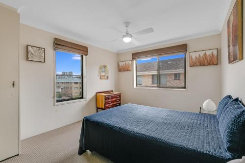 a bedroom with a blue bed and two windows at Unit 7 18 Endeavour Parade in Tweed Heads