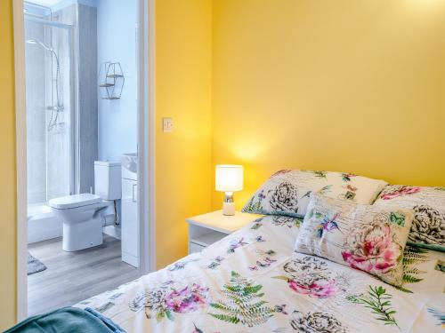 a bedroom with yellow walls and a bed and a bathroom at Tynrhos Lake View in Cilcennin
