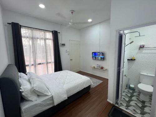 a bedroom with a bed and a bathroom with a shower at A’Casa Cottage in Kuala Terengganu