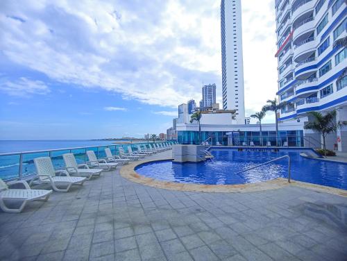 ein Resortpool mit Stühlen und das Meer in der Unterkunft Apartamentos Palmetto - Frente al Mar in Cartagena de Indias