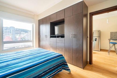 a bedroom with a bed and a large window at Hermosa Suite, siéntete en casa! in Quito