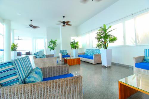 una sala de estar con sofás, sillas y plantas. en Apartamentos Palmetto - Frente al Mar en Cartagena de Indias