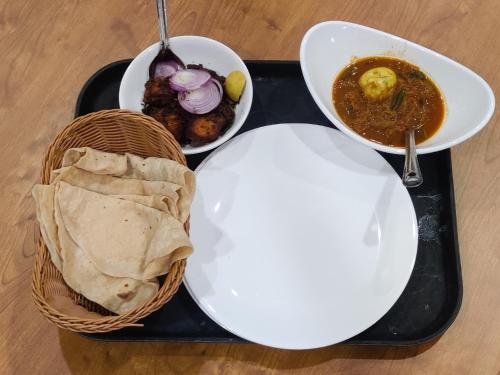 een zwart dienblad met twee schalen eten en een kom soep bij Cloud Canopy - Tea Garden Family Pool Cottage in Vagamon in Vagamon
