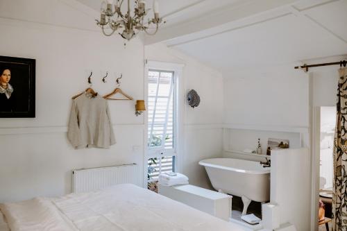 a white bedroom with a sink and a bed and a tub at Jacks Garden Cottage at Poets Lodge in Daylesford