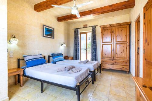 2 camas en una habitación con ventana en Ta Guljetta 4 bedroom Villa with private pool, en Marsalforn
