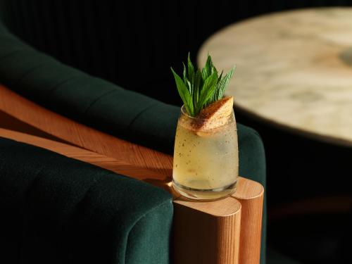 a drink sitting on top of a wooden table at The Porter House Hotel Sydney - MGallery in Sydney