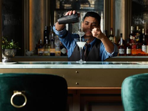 a man pouring a drink at a bar at The Porter House Hotel Sydney - MGallery in Sydney