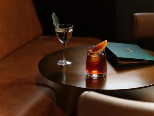 a table with a drink and a glass on it at The Porter House Hotel Sydney - MGallery in Sydney